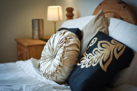 Comfortable double bedroom with a wooden headbo...