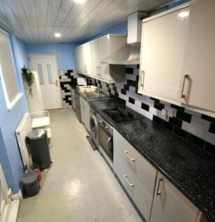 Long galley kitchen with sleek black speckled c...