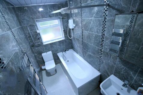 Modern tiled bathroom with a white bath, toilet...