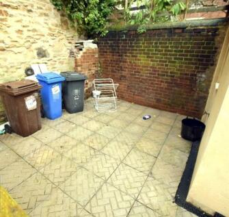 Low¿maintenance paved courtyard with high brick...