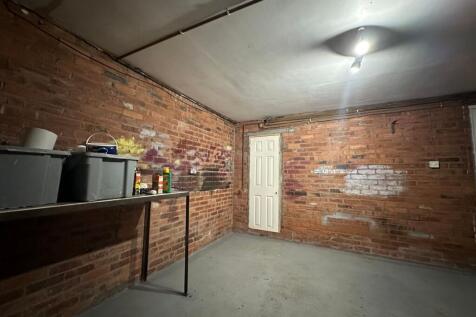 Red-brick walled storage room with a concrete f...