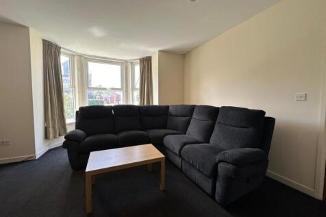 Bright bay-window living room with a large comf...