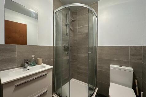 Modern tiled bathroom with a corner glass showe...