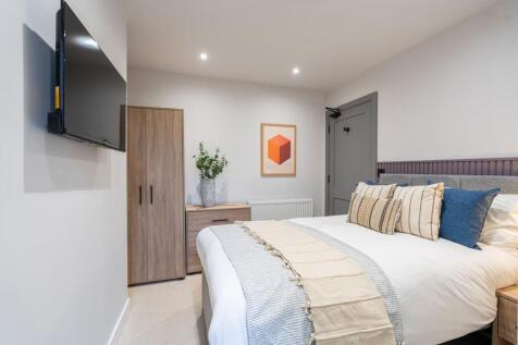 A stylish and spacious master bedroom featuring...