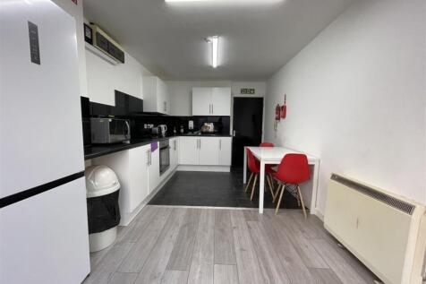Modern communal kitchen with white cabinets, bl...