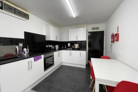 Modern shared kitchen with white cabinetry, bla...