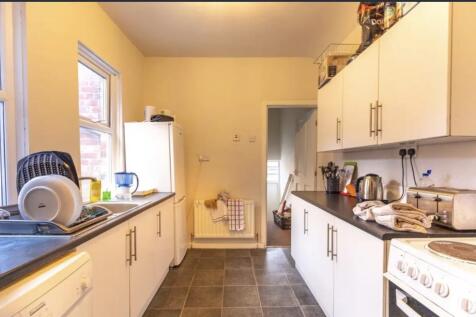 Bright galley kitchen with white cabinets, dark...