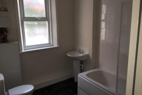 Bright, clean bathroom with a bathtub and showe...