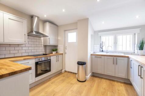 Bright, modern kitchen with wood countertops, i...