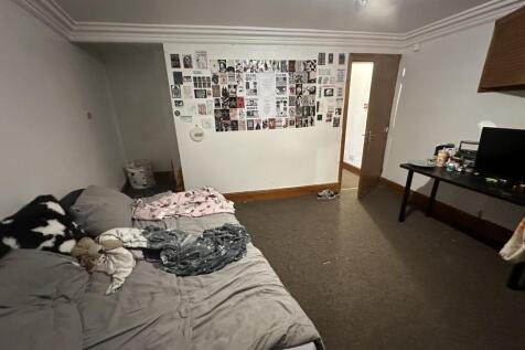A well-lit double bedroom featuring a large bed...