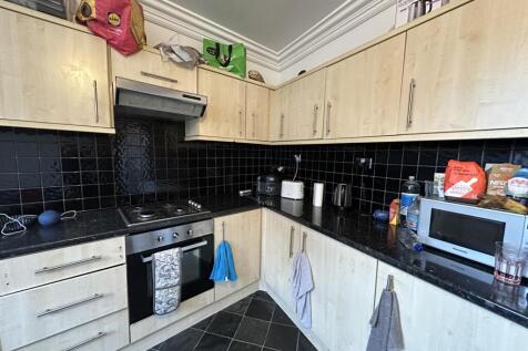 A modern kitchen with black tiled backsplash an...