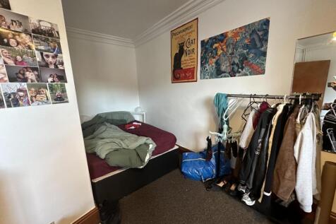 A cozy bedroom featuring a single bed, a small ...