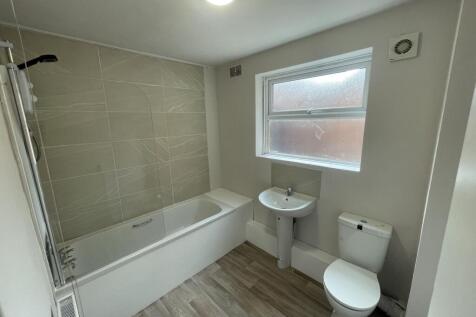 Bright, modern bathroom with a tiled bath/showe...
