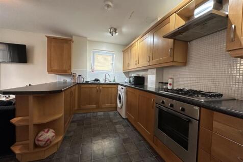 Well-equipped galley kitchen with wood cabinetr...
