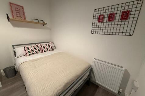 Cozy double bedroom with a neatly made bed, neu...