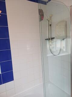 Bright tiled bathroom with a white bath and cur...