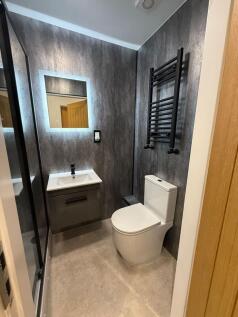 Modern ensuite bathroom with a sleek wall-mount...