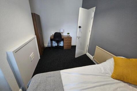 A cozy single bedroom featuring a comfortable b...