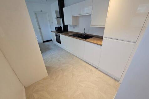A modern kitchen featuring sleek white cabinetr...