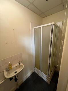 A compact bathroom featuring a corner shower cu...