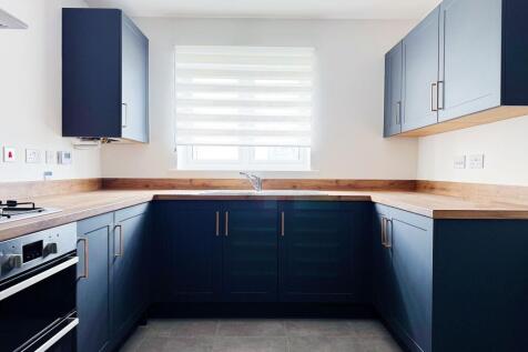 Bright, modern kitchen with deep navy shaker ca...