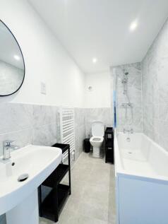 Bright, modern bathroom with a bathtub and show...