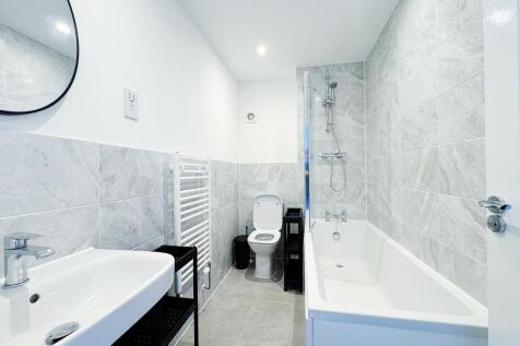 Bright, modern bathroom with a full bathtub and...