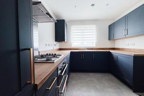 Modern L-shaped kitchen with dark cabinetry, wo...
