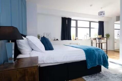 Bright, modern master bedroom with a neatly mad...