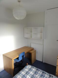 A cozy student bedroom featuring a simple woode...