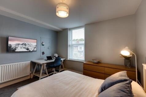 Bright, neatly styled bedroom with a comfortabl...