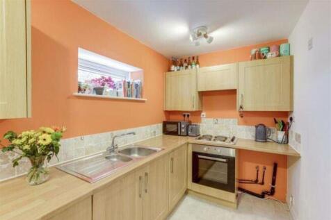 This modern kitchen features a vibrant orange a...