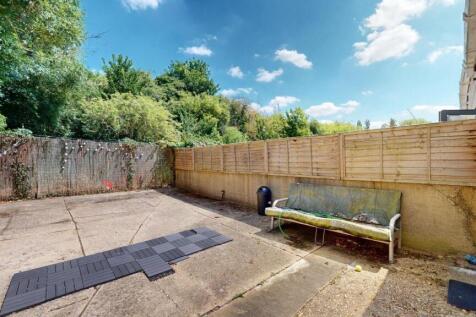 A spacious and sunny garden area with a paved s...