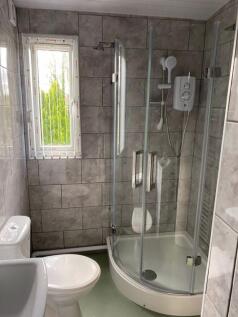 A modern bathroom suite featuring a curved glas...