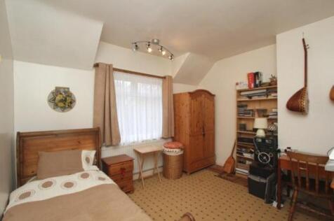 A cozy single bedroom featuring a wooden bed wi...