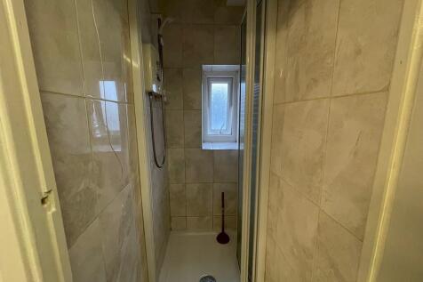 A compact and clean shower room featuring tiled...