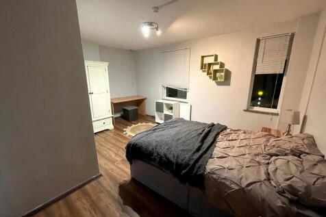 A cozy double bedroom featuring wood-effect flo...