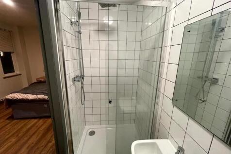 A modern ensuite bathroom featuring white tiled...