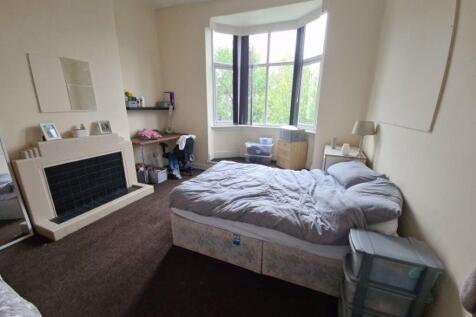 A spacious master bedroom featuring a large bay...