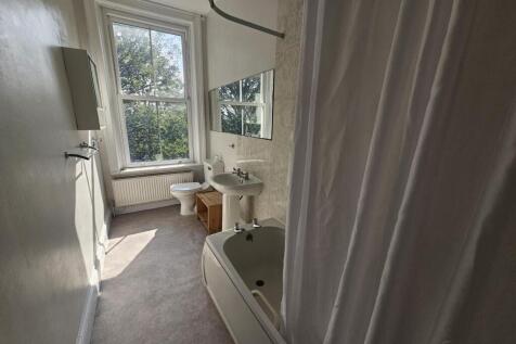A bright and clean bathroom with a large bathtu...