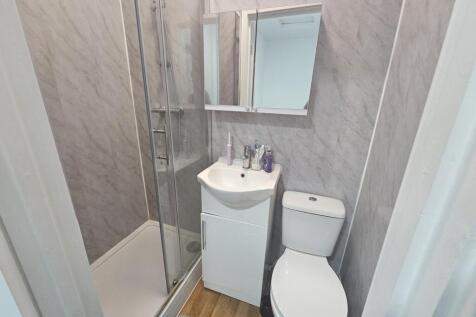 A modern bathroom with a compact shower unit, a...