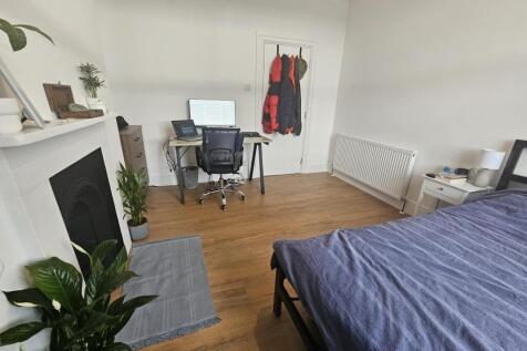 A bright and tidy bedroom featuring a comfortab...