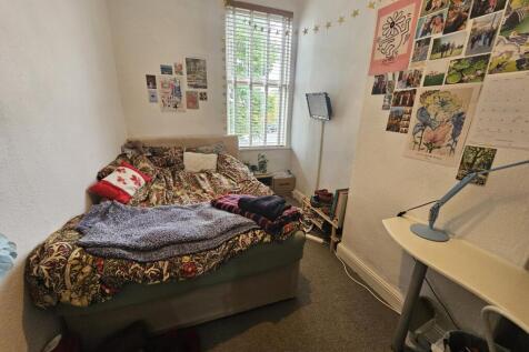 A cozy bedroom featuring a bed with colorful be...