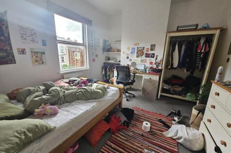 A cozy bedroom filled with personal belongings,...