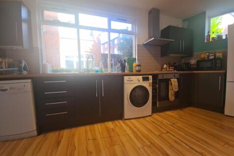 A modern, well-lit kitchen with dark cabinetry,...