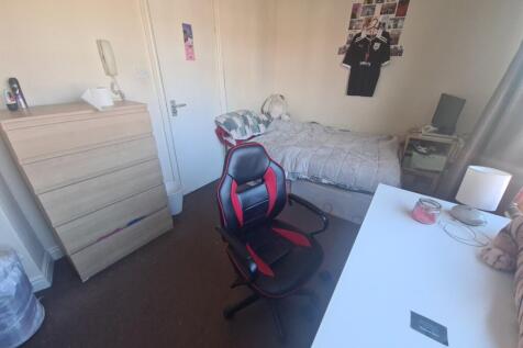 A cozy bedroom featuring a single bed, a desk, ...