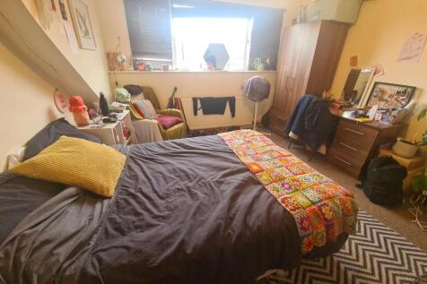 A cozy bedroom with a double bed covered in dar...