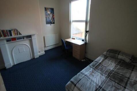 A cozy student bedroom featuring a bed near the...