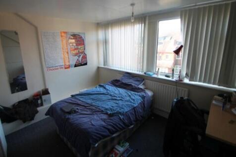 A cozy bedroom featuring a neatly made bed near...