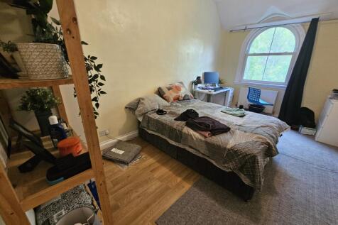 A cozy bedroom featuring a bed with bedding, a ...